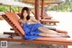 A woman in a blue towel laying on a lounge chair on the beach.