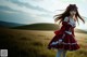 A woman in a red dress standing in a field.