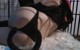 A woman in a black lingerie laying on a white rug.