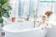 A woman sitting in a bathtub in a bathroom next to a window.