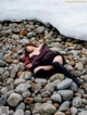 A woman laying on a rocky beach next to the ocean.