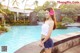 A woman standing next to a swimming pool with a flower in her hair.