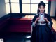 A woman in a black and white kimono sitting on the floor.