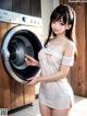 A woman in a white dress standing next to a washing machine.